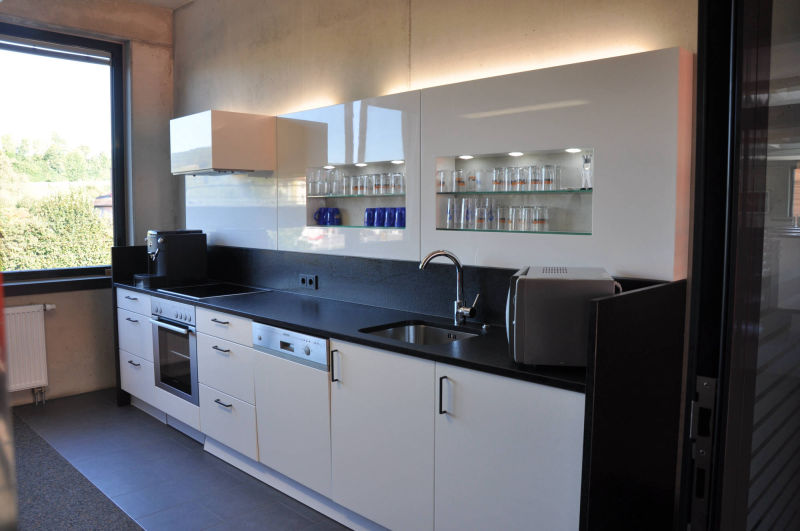 Weiß Hochglanz Küchenzeile mit Wandregalvorbau mit integrierten Regalnischen und Dunstabzugshaube.